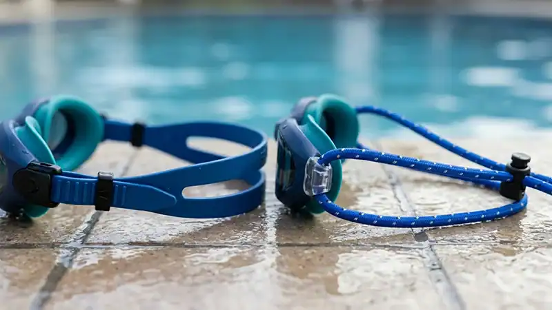 Bungee cord and silicone goggle straps compared beside a pool.