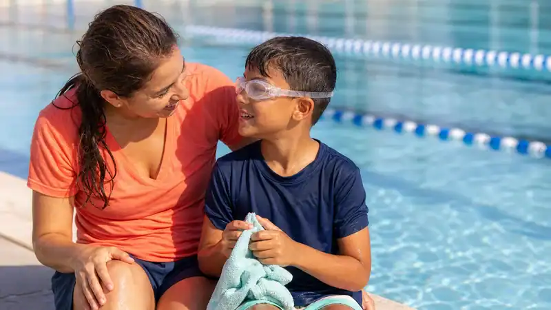 Parent and child smiling poolside after a beginner swim lesson